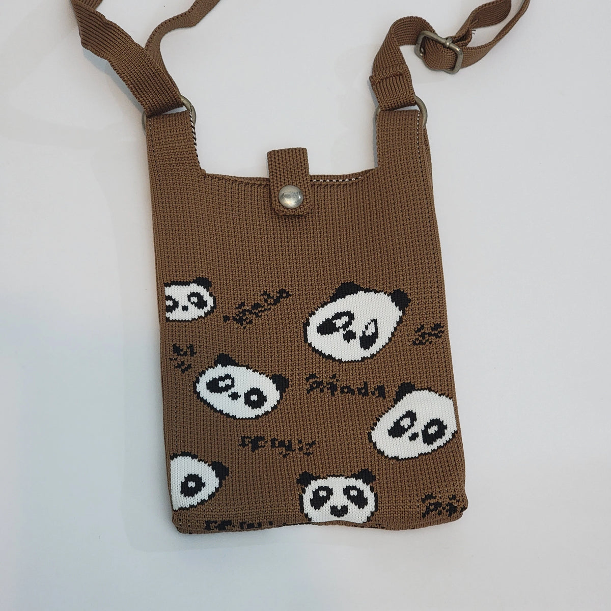 A brown knitted crossbody phone bag with a panda print pattern, featuring a small metal snap button closure and an adjustable shoulder strap, shown on a plain white background.