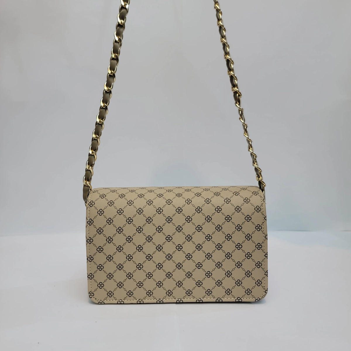 A vintage-style shoulder bag with a beige and black monogram pattern, featuring a gold-tone chain strap, set against a plain light gray background.