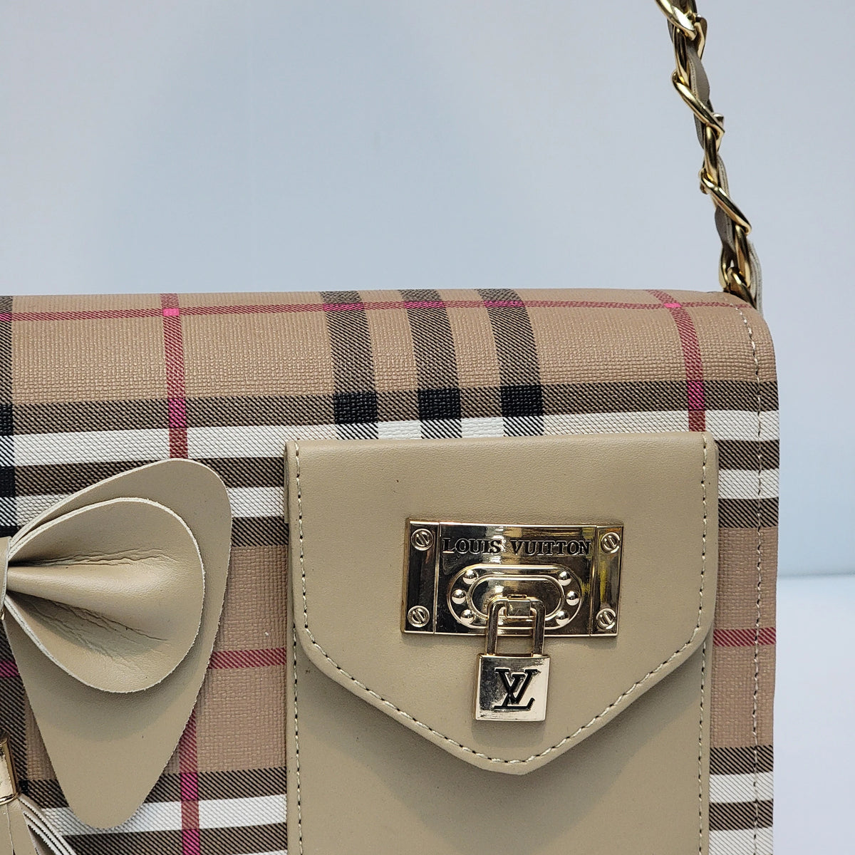 Louis Vuitton shoulder bag featuring the classic beige tartan plaid pattern with black, white, and pink stripes, a beige leather bow detail on the left, and a beige leather front flap secured by a gold-tone Louis Vuitton lock and chain strap.
