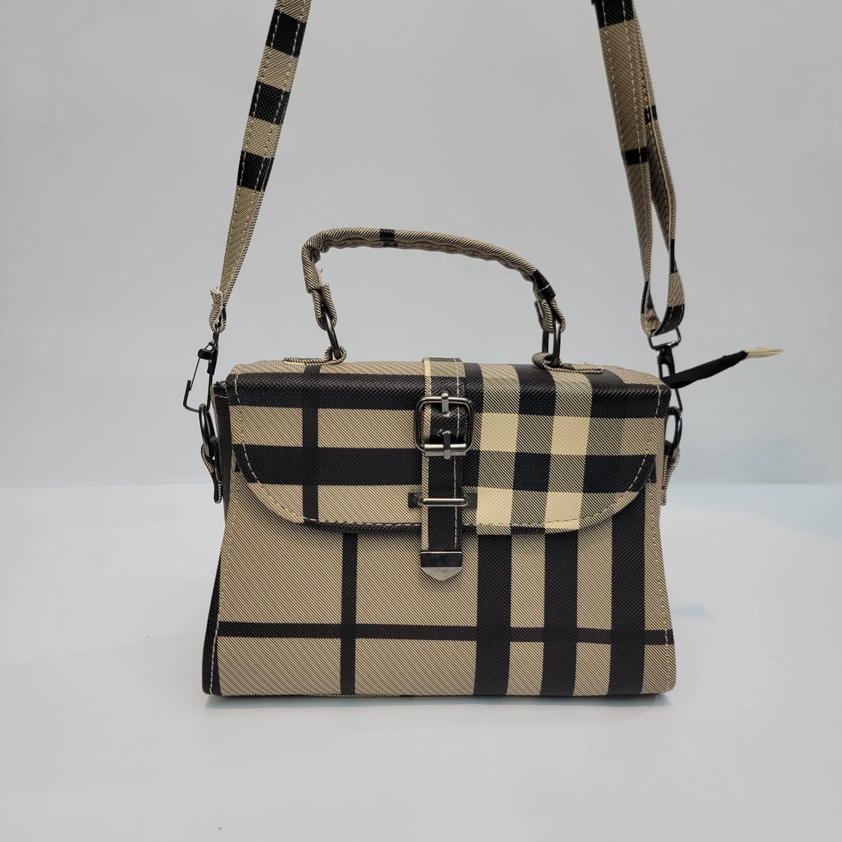 A structured handbag with a beige and black plaid pattern, featuring a top handle, a detachable shoulder strap, and a front flap secured by a buckle.