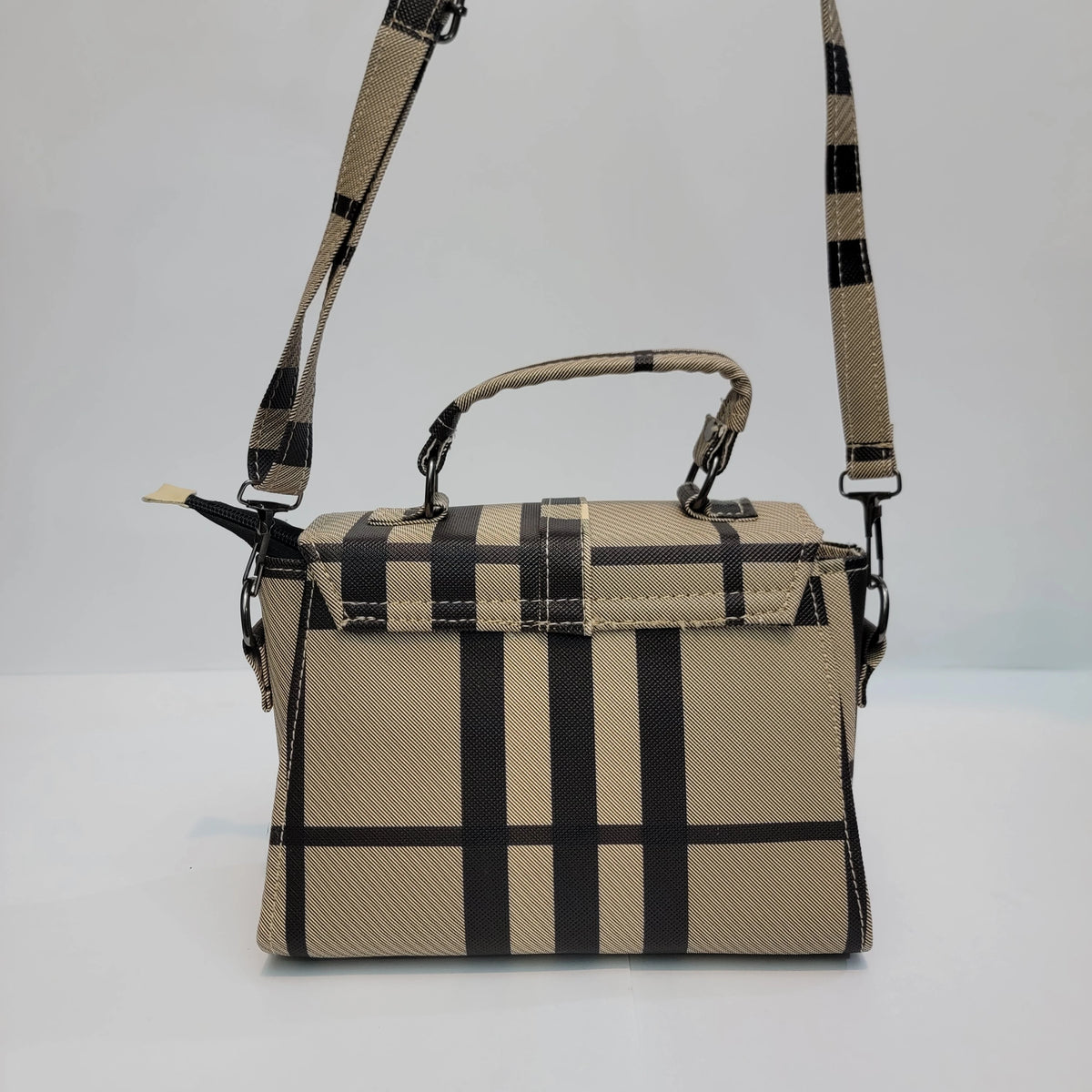A structured handbag with a beige and black plaid pattern, featuring a top handle, a shoulder strap, and a zip-around closure, photographed against a plain light gray background.