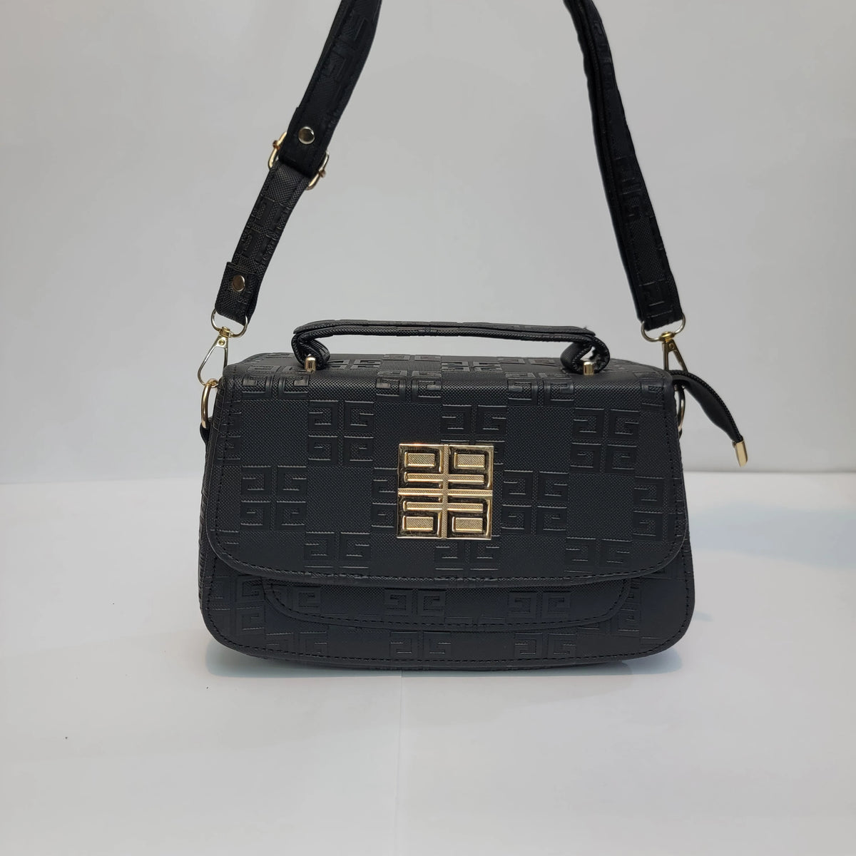 Black embossed leather handbag with a top handle, adjustable shoulder strap, and a gold-toned geometric logo clasp on the front.
