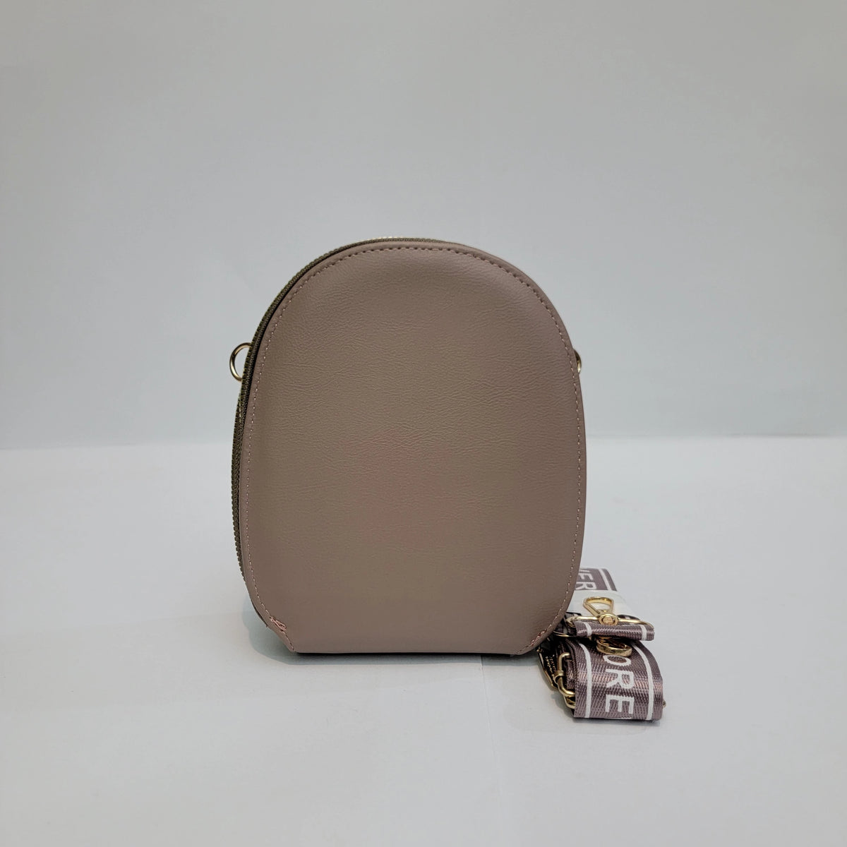 A small, dome-shaped beige leather pouch with a gold-tone zipper and a matching beige and gold brand strap featuring the text 'DURE'.