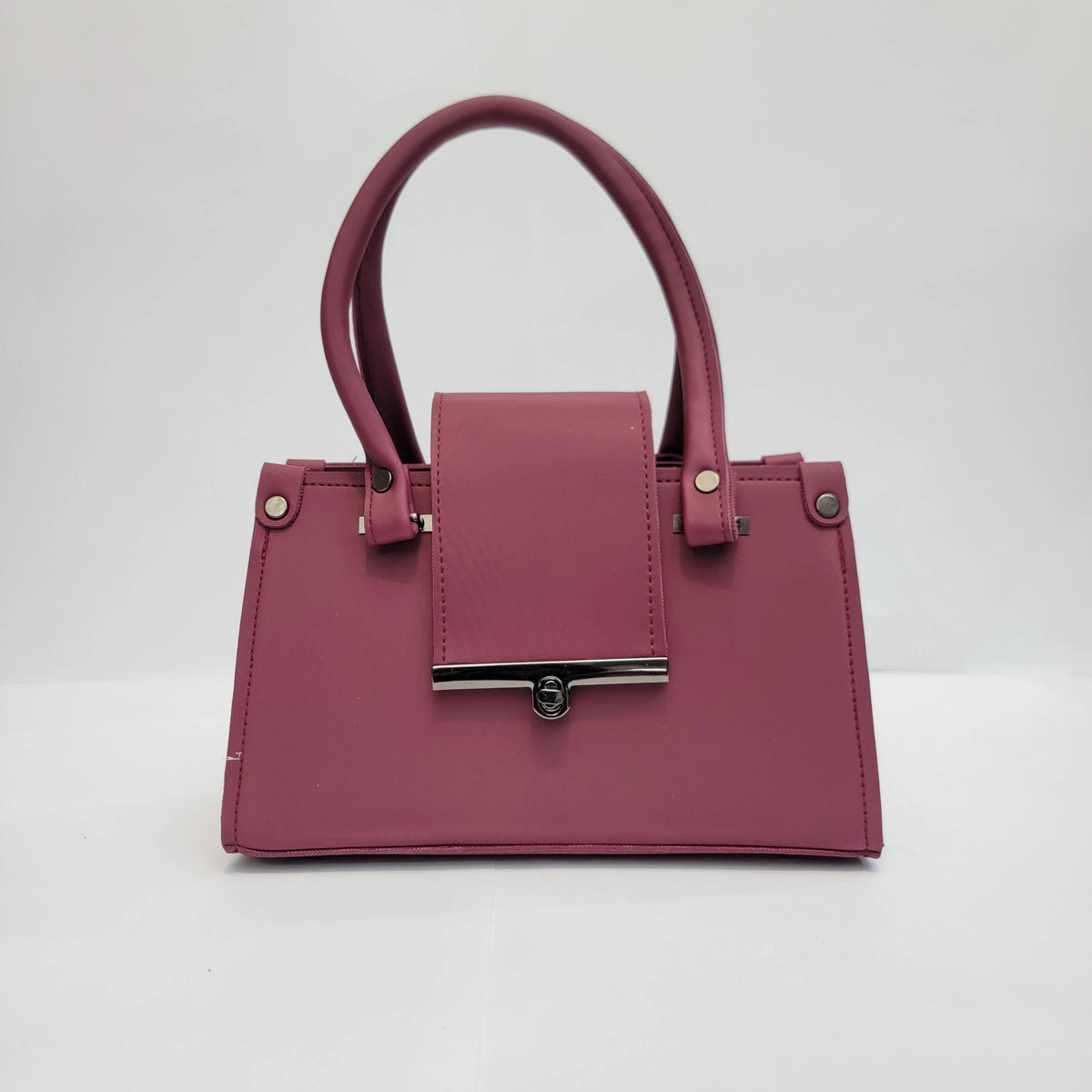 A structured magenta handbag with dual top handles, a front flap, and silver-tone hardware, photographed against a plain light gray background.
