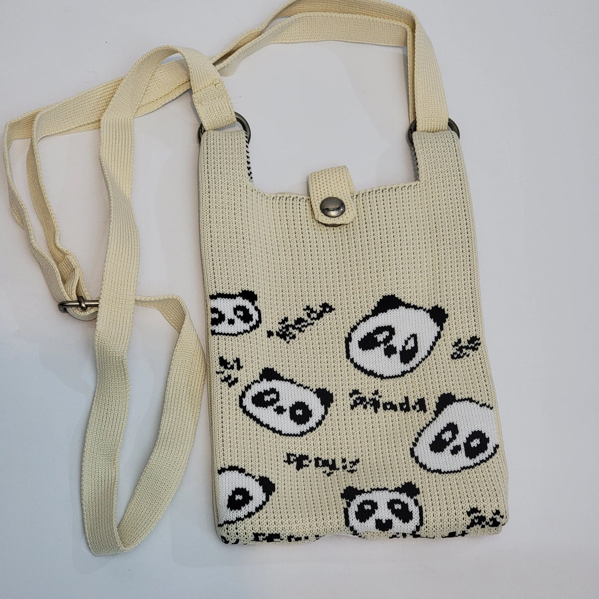A cream-colored knitted shoulder bag with a black and white panda print and a matching adjustable shoulder strap, shown on a plain white background.