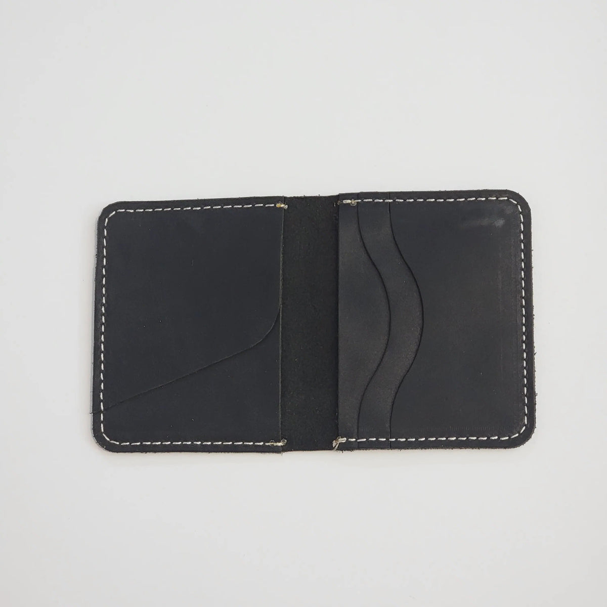 A minimalist black leather card holder wallet with white contrast stitching, shown open against a plain white background.