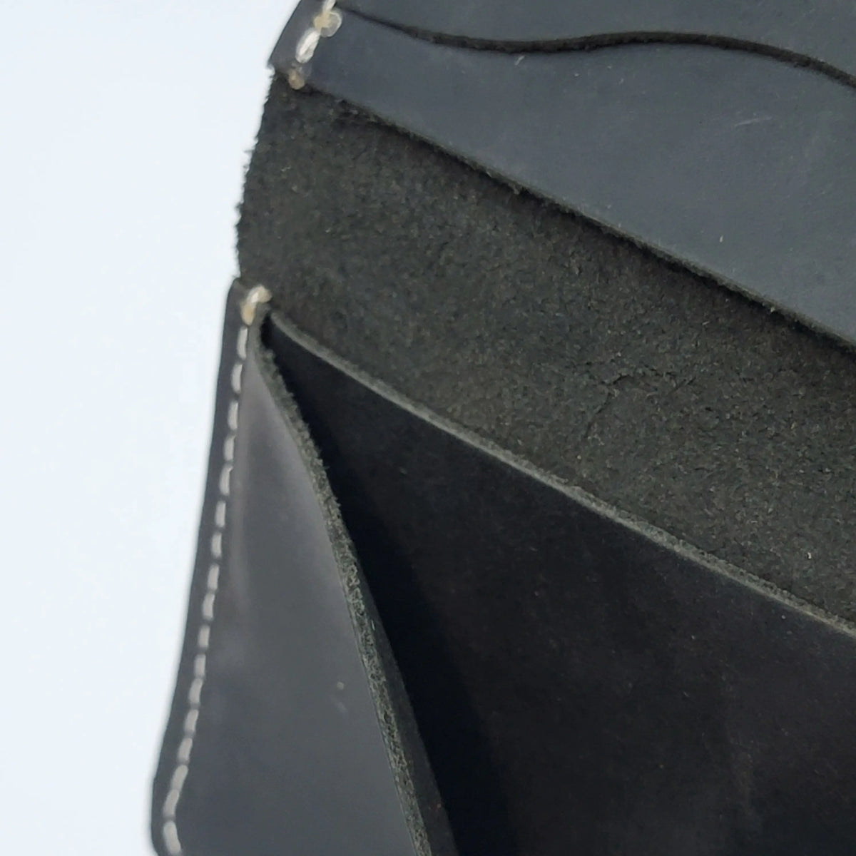 A small black leather card holder wallet, close-up of stitching detail