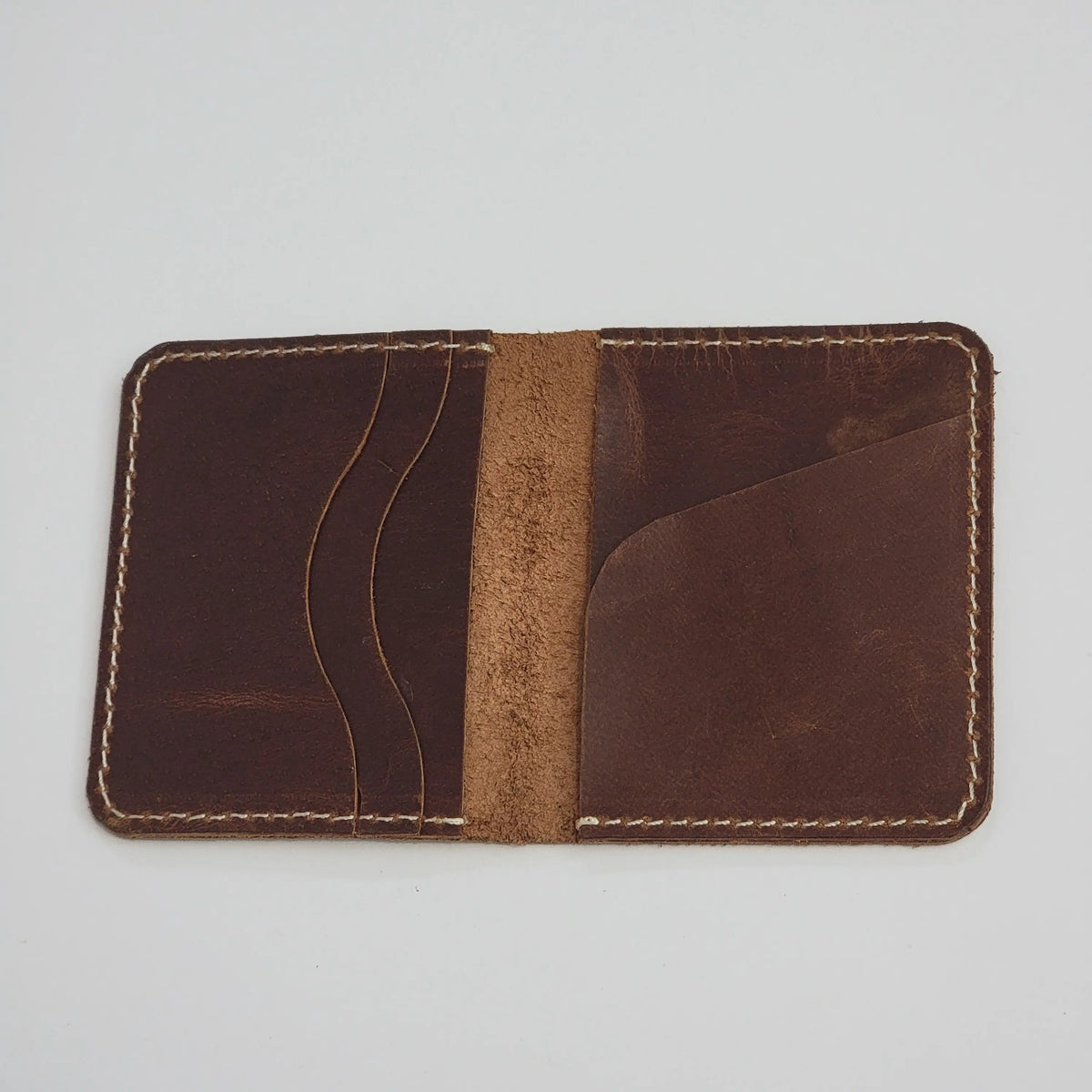 A dark brown leather card holder wallet with light tan contrast stitching, shown open against a light gray background.