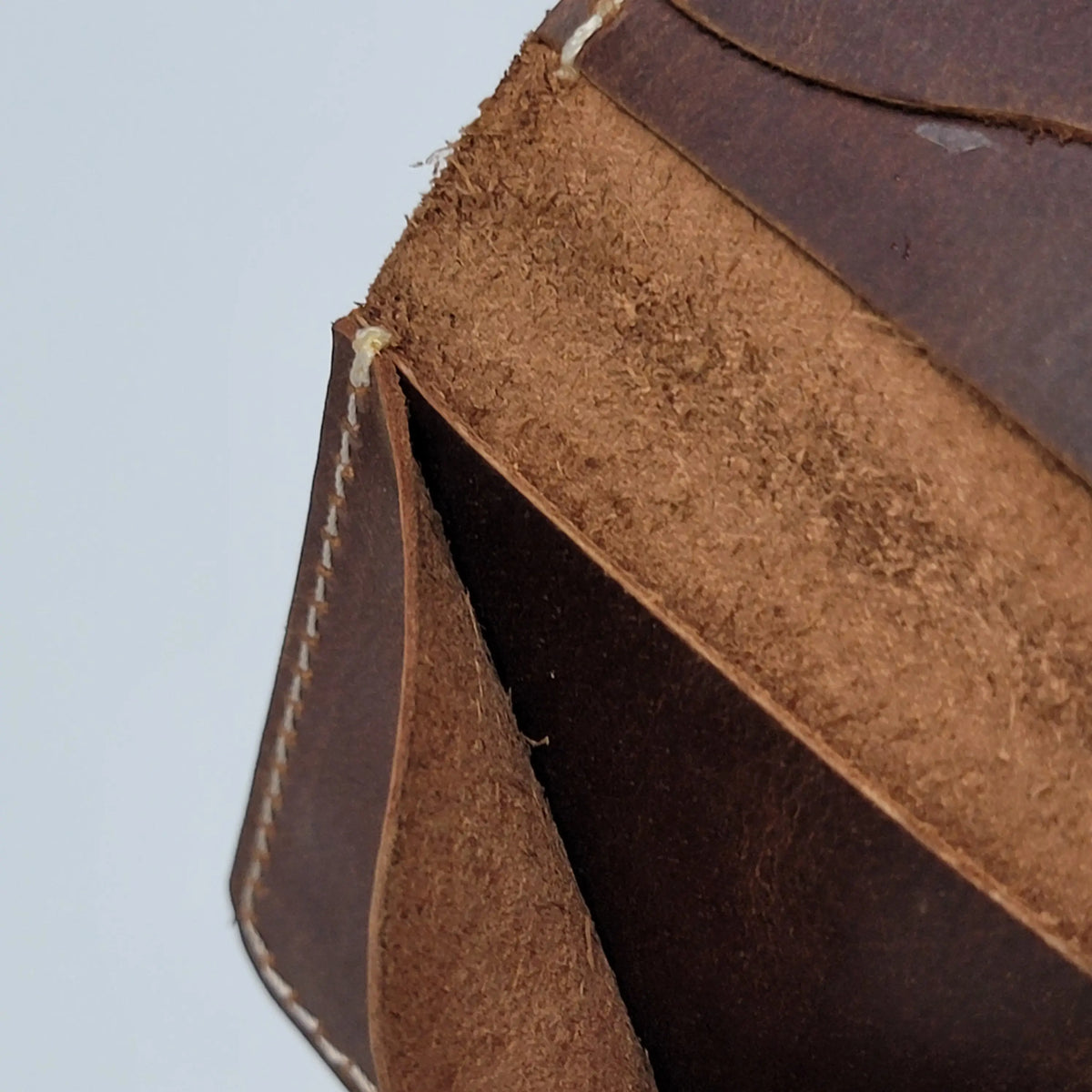 A small brown leather card holder wallet, close-up of stitching detail