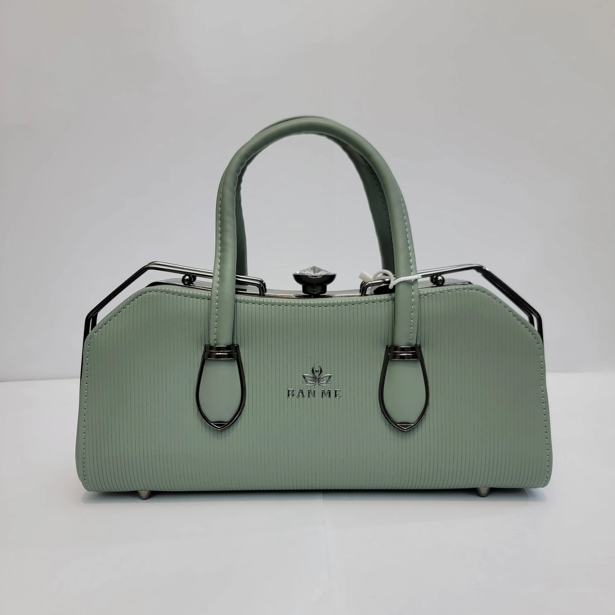 A sage green textured handbag with a top handle, black metal side supports, and silver-tone hardware, featuring the brand name 'HARPE' on the front, set against a plain light gray background.