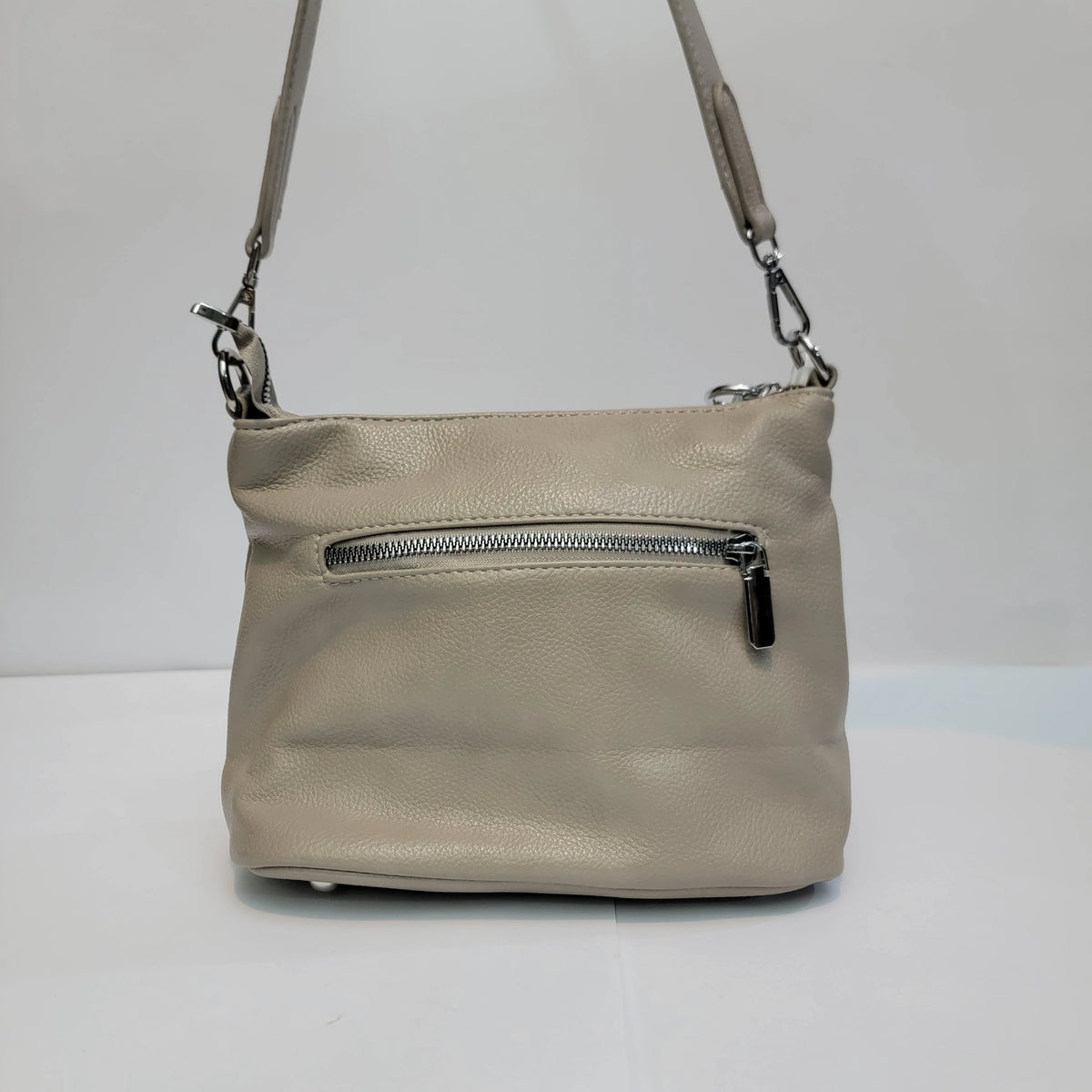 A light beige pebbled leather shoulder bag with a front zippered pocket and a matching adjustable shoulder strap, shown against a plain white background.