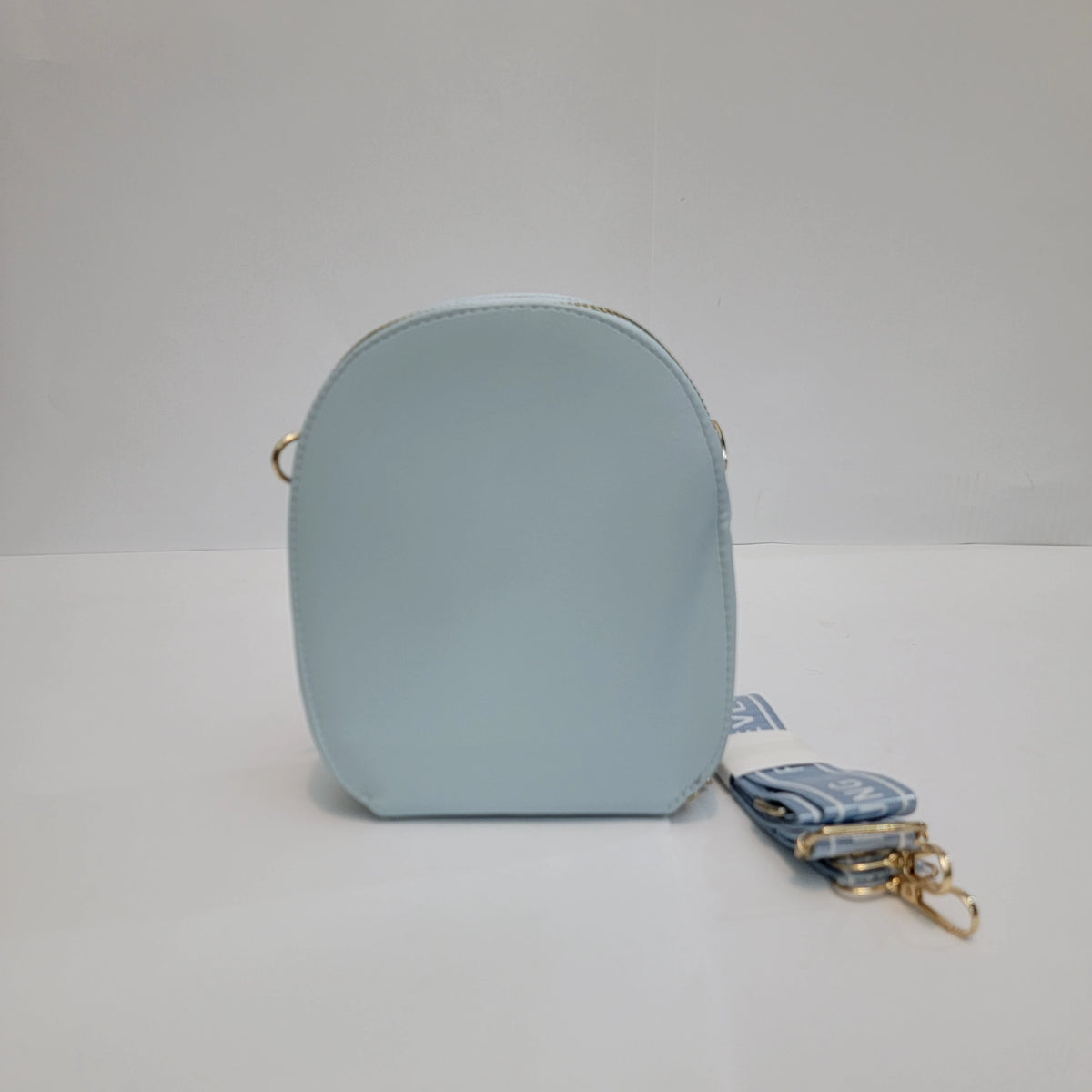 A small light blue faux-leather crossbody bag with a matching blue patterned fabric strap and gold-tone hardware, shown on a plain white studio background.