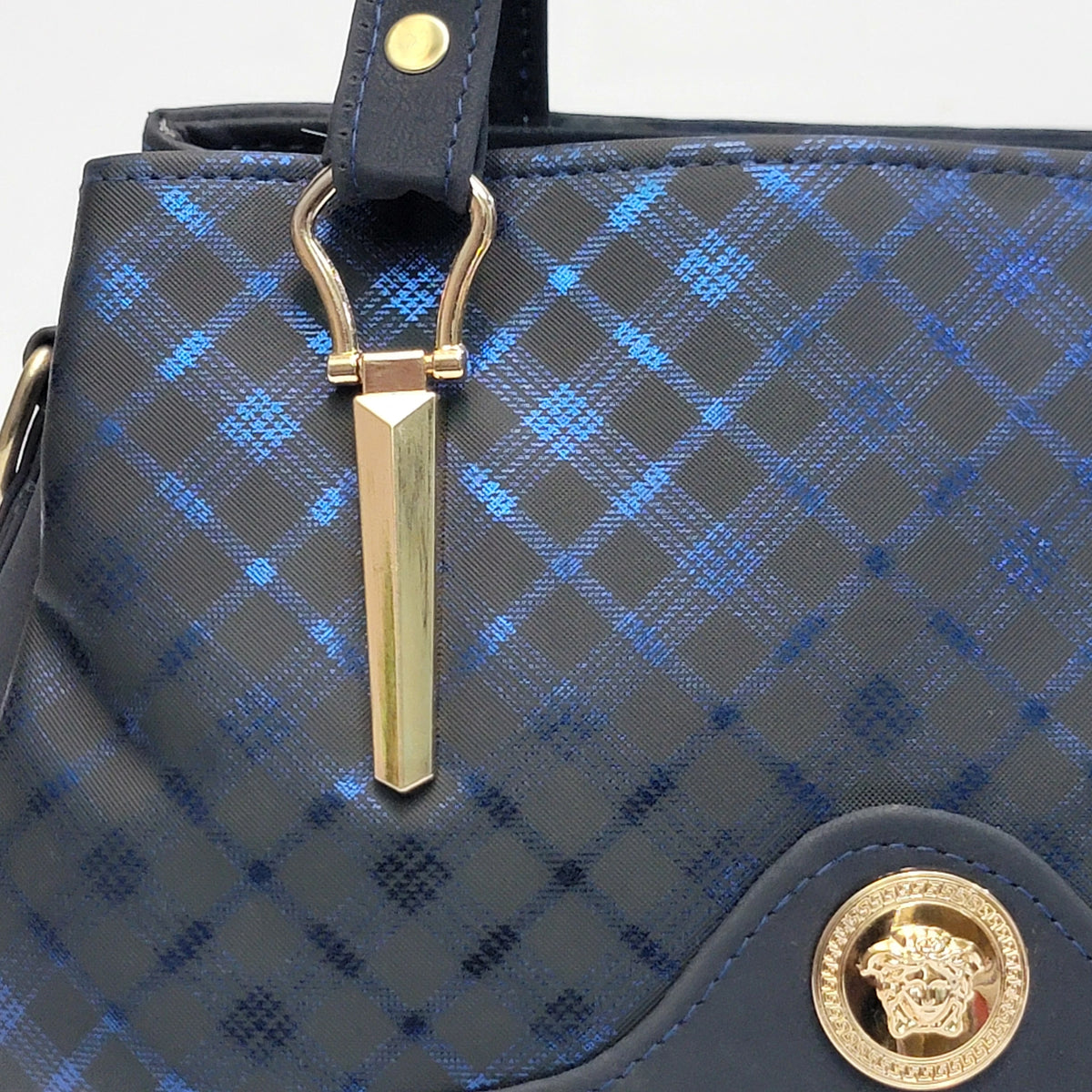 Close-up of a Versace handbag featuring a blue and black diamond-patterned canvas body, gold-tone hardware, and the signature Medusa emblem on a dark leather patch.