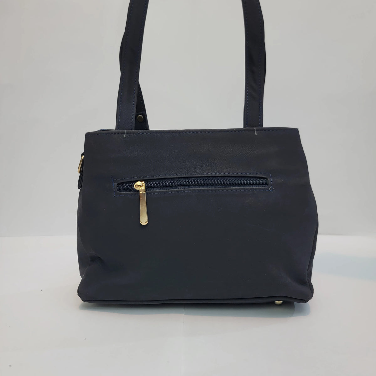 A dark navy blue tote bag with a front zippered pocket featuring a gold-tone zipper pull, shown against a plain light gray background.