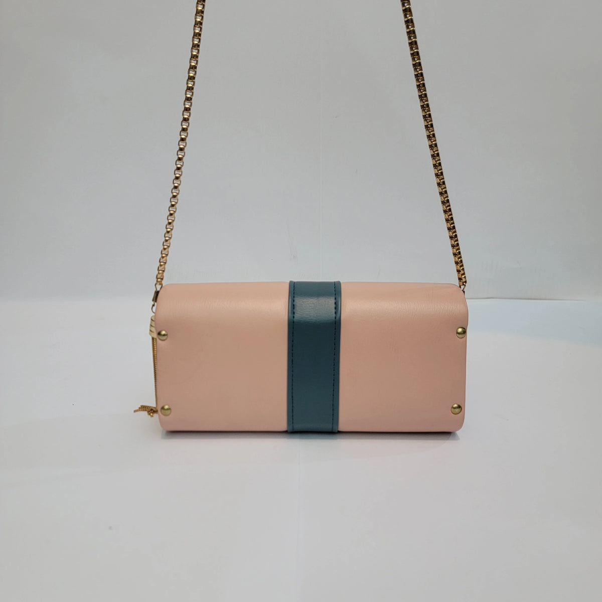 A rectangular shoulder bag in light pink faux leather with a vertical dark teal stripe down the center and gold-tone chain straps, shown against a plain light gray background.