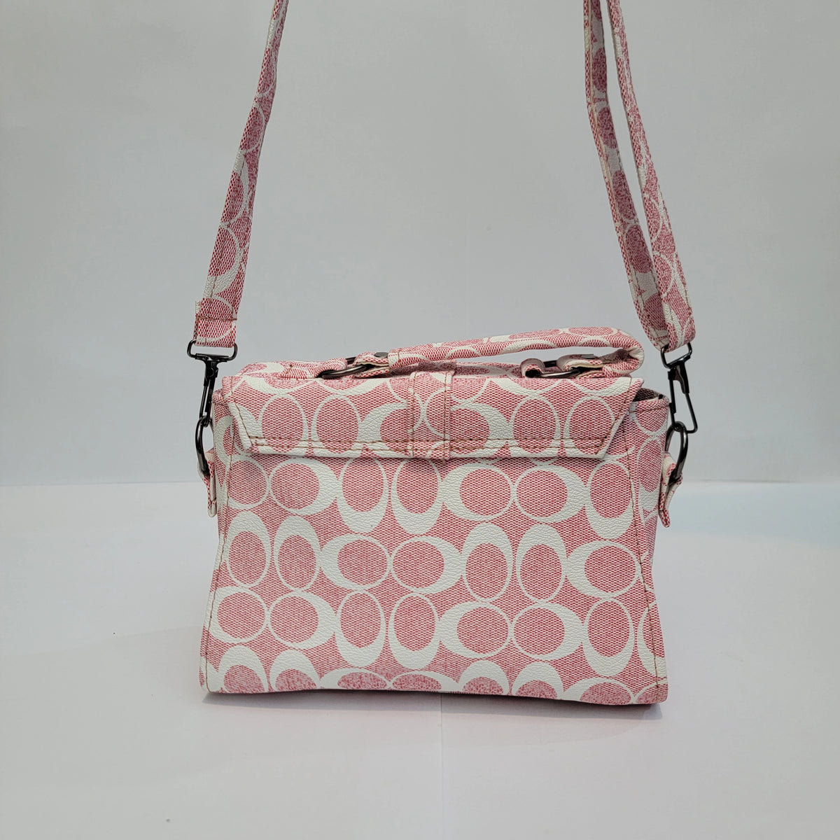 A pink and white patterned crossbody handbag with a matching shoulder strap, displayed against a plain light gray background.